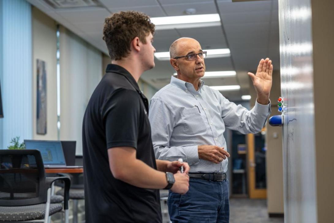 A School of Management Kettering professor teaches a student as both stand in front of a whiteboard